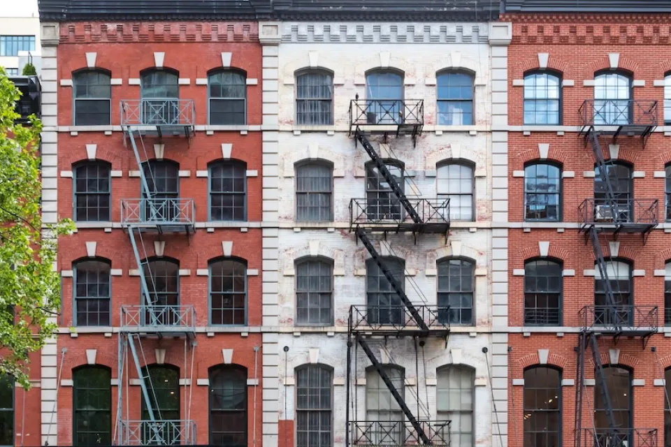 Brick New York City apartment buildings with fire escapes.